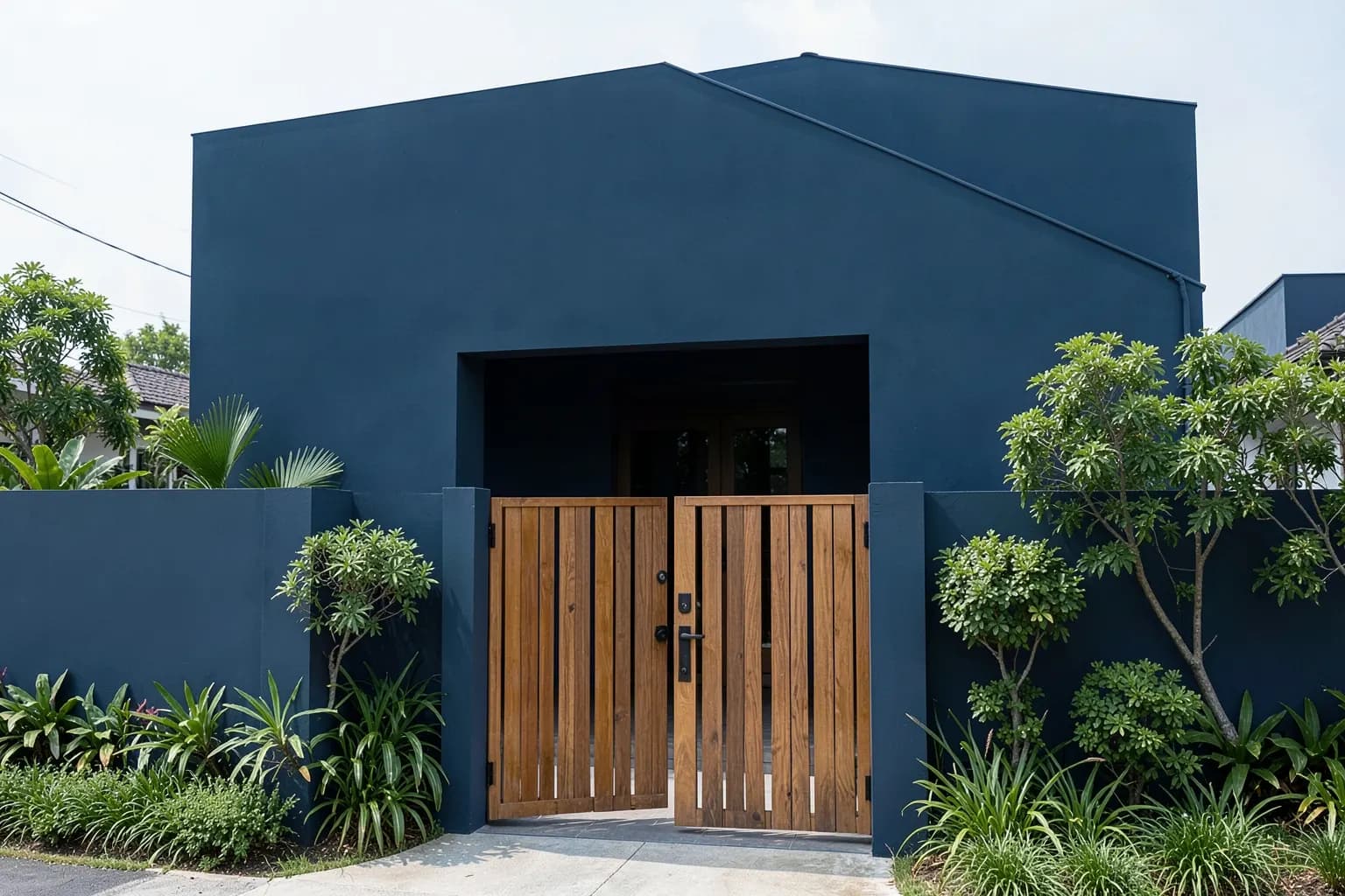 Fachada de casa simples com portão de madeira entreaberto e plantas ao redor.