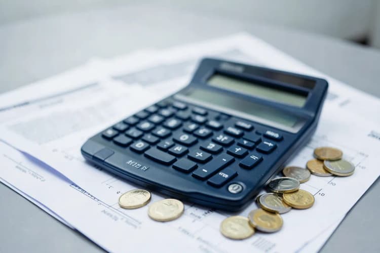 Uma calculadora e moedas sobre papéis de cartório.
