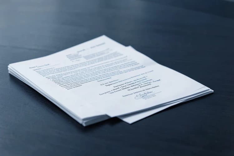 Uma pilha de documentos legais e um contrato de casamento em cima de uma mesa de madeira escura.