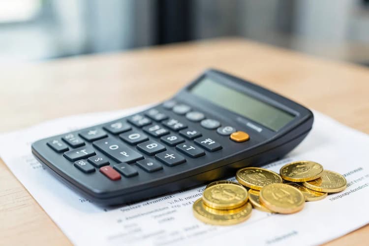 Calculadora e moedas de ouro sobre um contrato imobiliário.